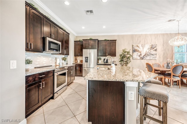 kitchen featuring pendant lighting, sink, a kitchen island with sink, stainless steel appliances, and dark brown cabinets