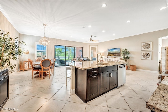 kitchen with sink, decorative light fixtures, stainless steel dishwasher, an island with sink, and light stone countertops