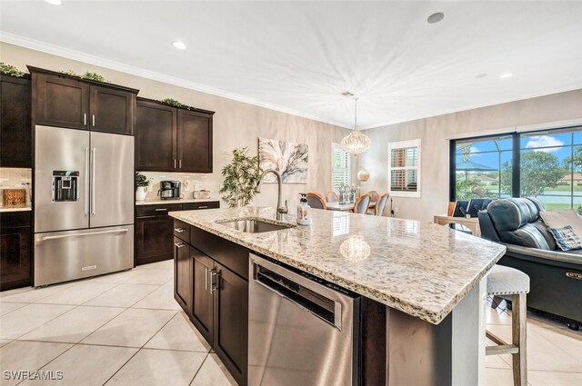 kitchen featuring sink, a kitchen island with sink, hanging light fixtures, stainless steel appliances, and dark brown cabinetry