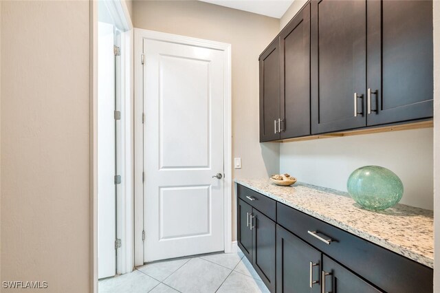 interior space with light stone countertops, dark brown cabinets, and light tile patterned floors