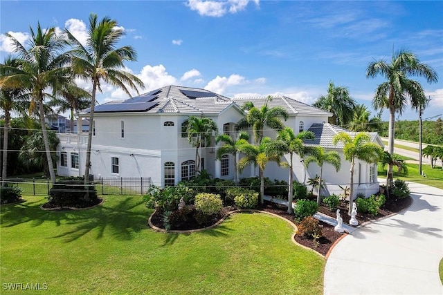 view of front of home with solar panels and a front lawn