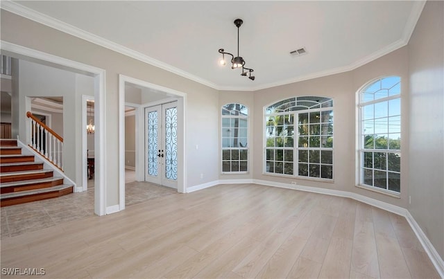 unfurnished dining area featuring french doors, ornamental molding, a notable chandelier, and light wood-type flooring