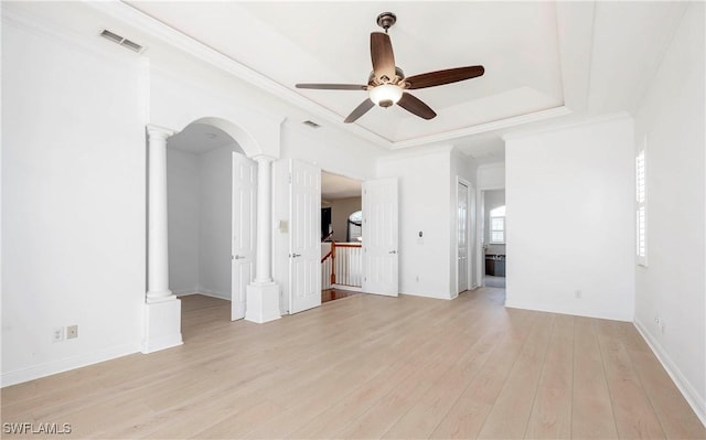 spare room featuring light wood-type flooring, ornate columns, a tray ceiling, ceiling fan, and crown molding