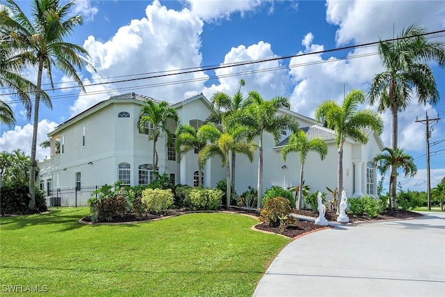 view of front of house with a front lawn, fence, cooling unit, and stucco siding