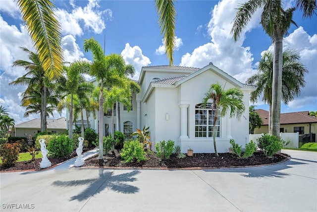 mediterranean / spanish house with driveway, fence, and stucco siding