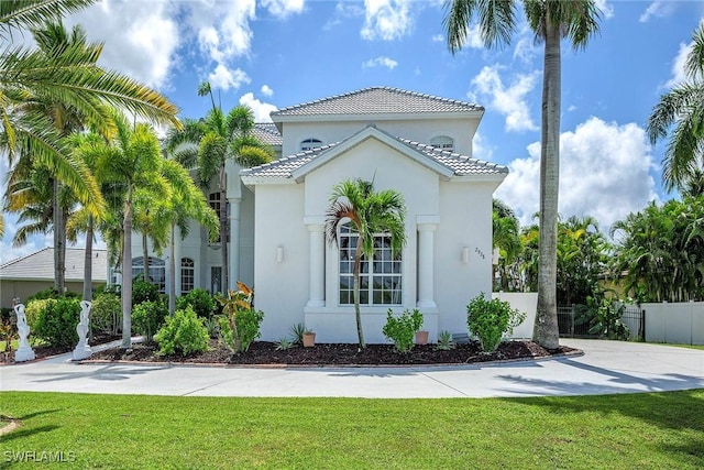 view of front of property featuring fence, a tiled roof, a front lawn, and stucco siding