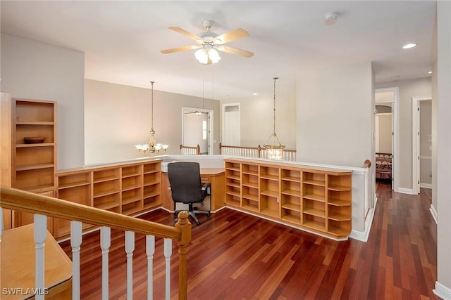 home office featuring recessed lighting, baseboards, dark wood-type flooring, built in desk, and ceiling fan with notable chandelier