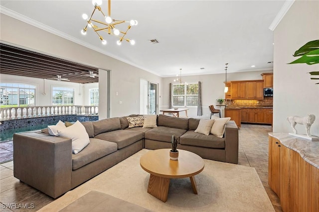 living room featuring a healthy amount of sunlight, visible vents, crown molding, and an inviting chandelier