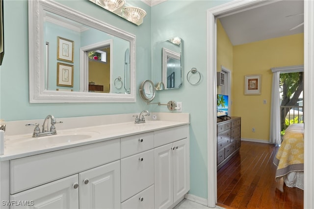 bathroom featuring wood-type flooring, ornamental molding, and vanity