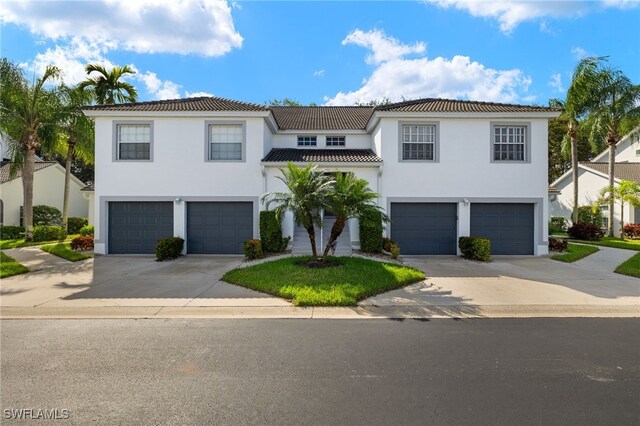 1010 Partridge Cir Unit 202, Naples, FL 34104 - view of front facade featuring an attached garage, concrete driveway, a tiled roof, and stucco siding