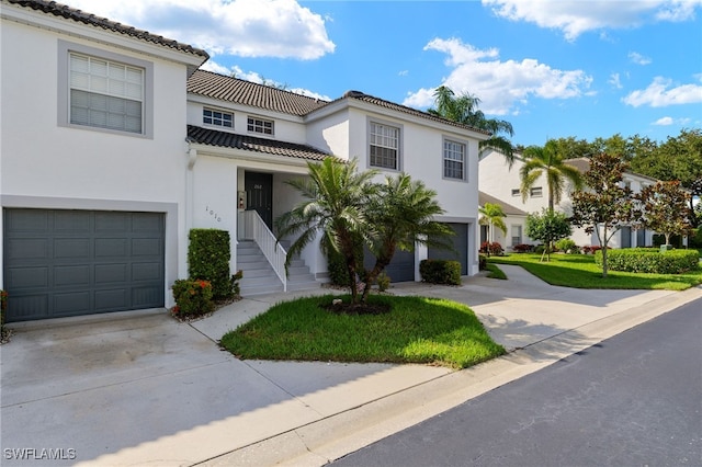 1010 Partridge Cir Unit 202, Naples, FL 34104 - view of front of home with an attached garage, concrete driveway, a tiled roof, and stucco siding