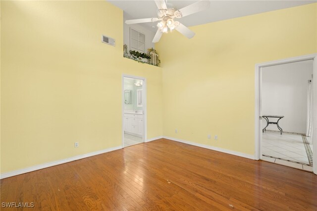 1010 Partridge Cir Unit 202, Naples, FL 34104 - empty room with ceiling fan, baseboards, a towering ceiling, and wood finished floors