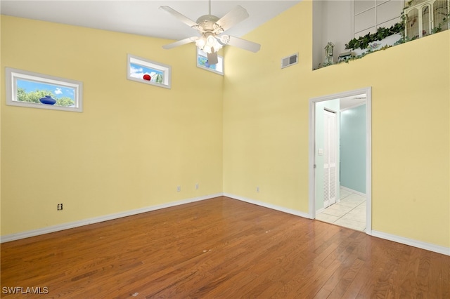 1010 Partridge Cir Unit 202, Naples, FL 34104 - empty room featuring wood finished floors, a ceiling fan, baseboards, and a towering ceiling