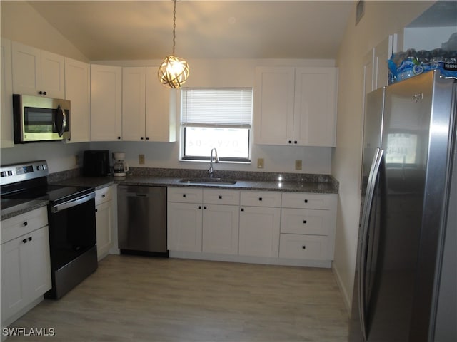 kitchen with light wood-type flooring, vaulted ceiling, sink, appliances with stainless steel finishes, and white cabinets