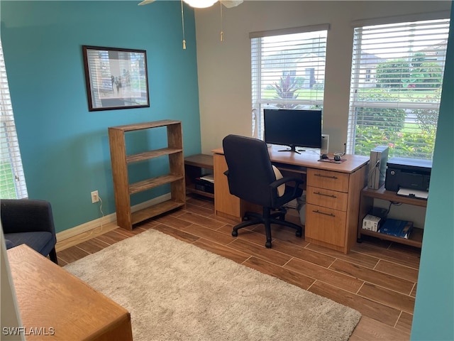 home office with ceiling fan, a wealth of natural light, and hardwood / wood-style flooring