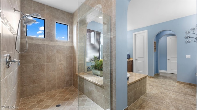 bathroom with tiled shower and vanity