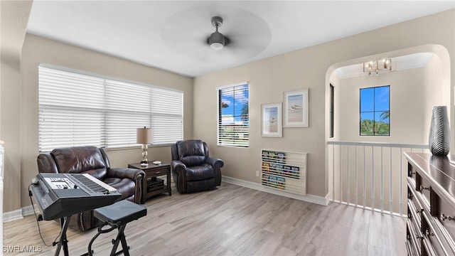 living area with ceiling fan with notable chandelier and light hardwood / wood-style flooring