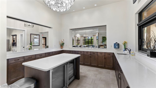 kitchen featuring beverage cooler, kitchen peninsula, sink, a chandelier, and light parquet flooring