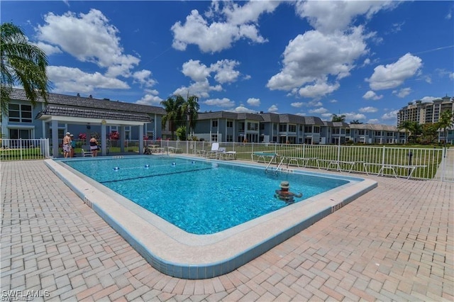 community pool with a patio area and fence