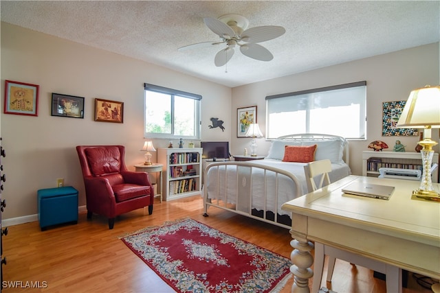 bedroom with a textured ceiling, ceiling fan, and hardwood / wood-style flooring