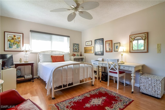 bedroom featuring ceiling fan, wood-type flooring, and a textured ceiling