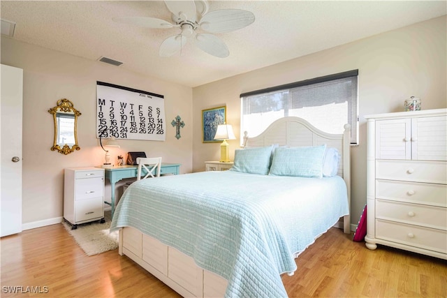 bedroom with a textured ceiling, light hardwood / wood-style flooring, and ceiling fan