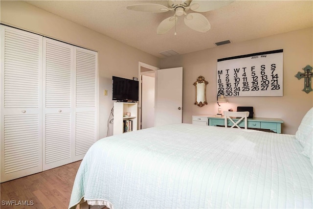 bedroom with a textured ceiling, light hardwood / wood-style flooring, ceiling fan, and a closet