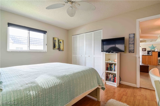 bedroom featuring a textured ceiling, light hardwood / wood-style flooring, ceiling fan, and a closet