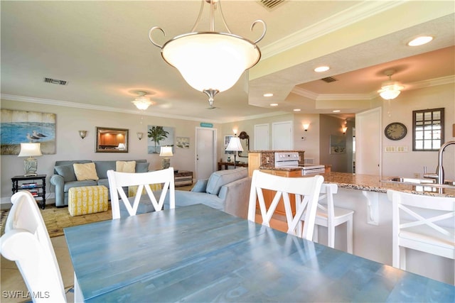 dining room with ornamental molding, a tray ceiling, sink, and ceiling fan