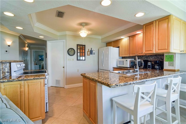 kitchen featuring crown molding, kitchen peninsula, a breakfast bar, and white appliances