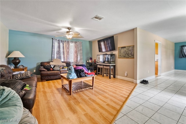 living room with light wood-type flooring, a textured ceiling, and ceiling fan