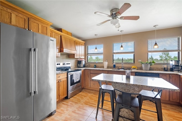 kitchen with custom exhaust hood, sink, ceiling fan, hanging light fixtures, and appliances with stainless steel finishes