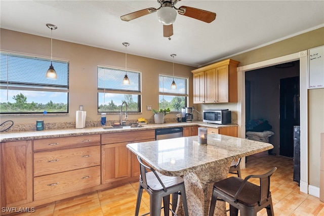 kitchen with stainless steel appliances, decorative light fixtures, sink, ceiling fan, and a breakfast bar area