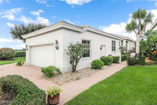 view of home's exterior with stucco siding, an attached garage, a lawn, and decorative driveway