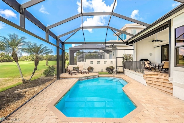 pool with a lanai, a yard, a patio area, and ceiling fan