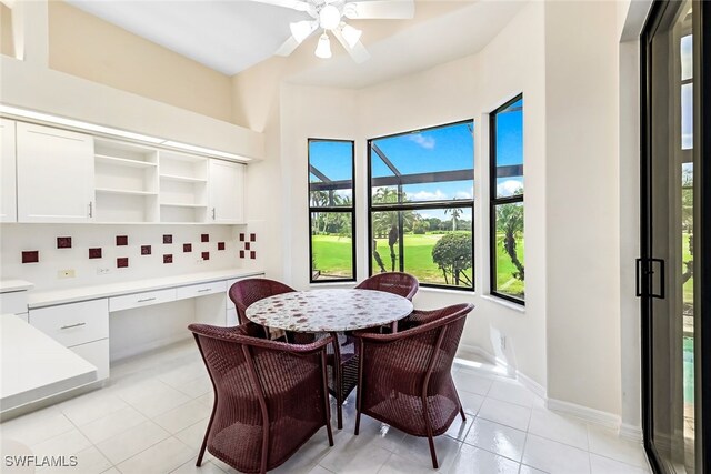 dining area featuring light tile patterned floors, built in desk, baseboards, and ceiling fan