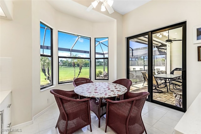 dining space featuring light tile patterned floors, a ceiling fan, baseboards, and a sunroom