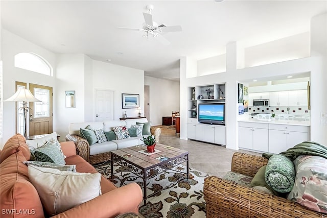 living room featuring built in features, a ceiling fan, and light tile patterned floors