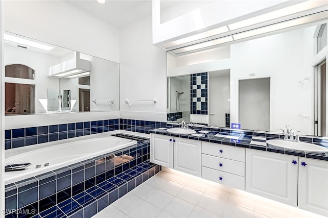 bathroom featuring tile patterned flooring, a garden tub, double vanity, and a sink