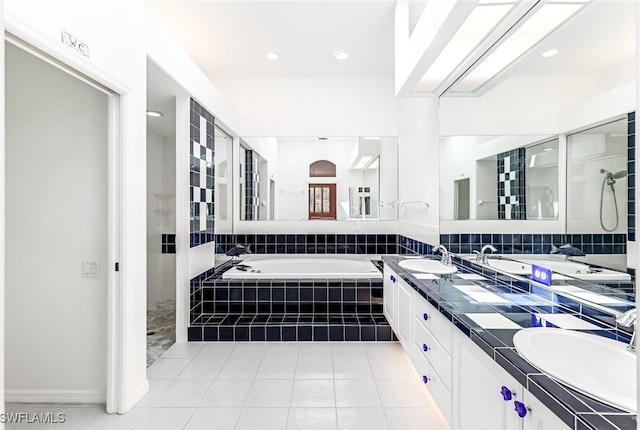 full bath with a sink, double vanity, a bath, and tile patterned floors