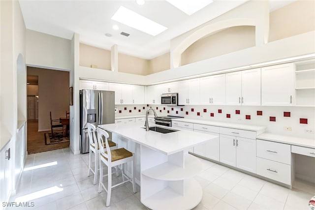 kitchen with open shelves, a sink, backsplash, white cabinetry, and stainless steel appliances