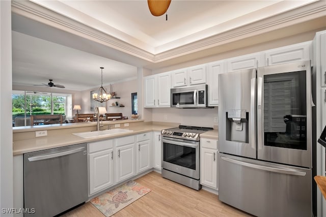 kitchen featuring ceiling fan with notable chandelier, stainless steel appliances, sink, kitchen peninsula, and white cabinetry