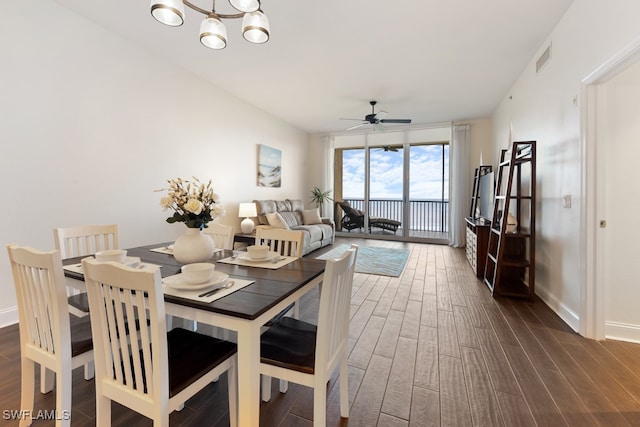 dining space with ceiling fan with notable chandelier and dark hardwood / wood-style floors