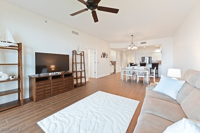 living room featuring dark wood-type flooring and ceiling fan with notable chandelier