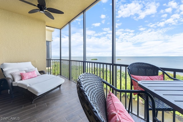 sunroom / solarium featuring plenty of natural light, ceiling fan, and a water view