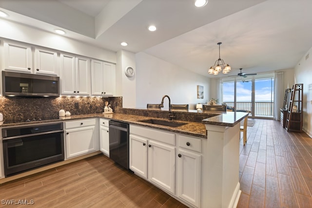 kitchen featuring black appliances, hardwood / wood-style floors, kitchen peninsula, and sink