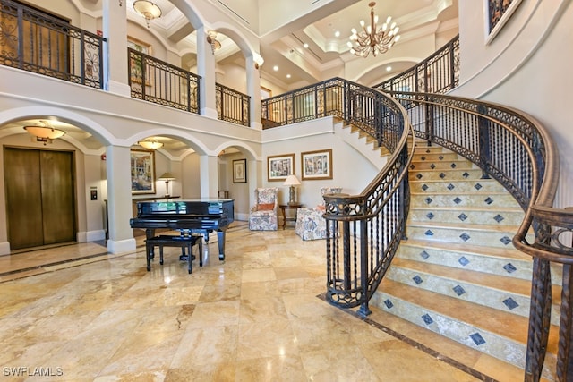 interior space featuring a notable chandelier, ornate columns, elevator, a high ceiling, and ornamental molding