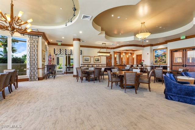 carpeted living room featuring crown molding, a notable chandelier, a tray ceiling, and ornate columns