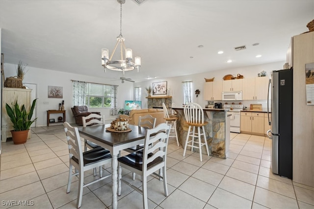 dining space featuring light tile patterned floors, an inviting chandelier, and a stone fireplace