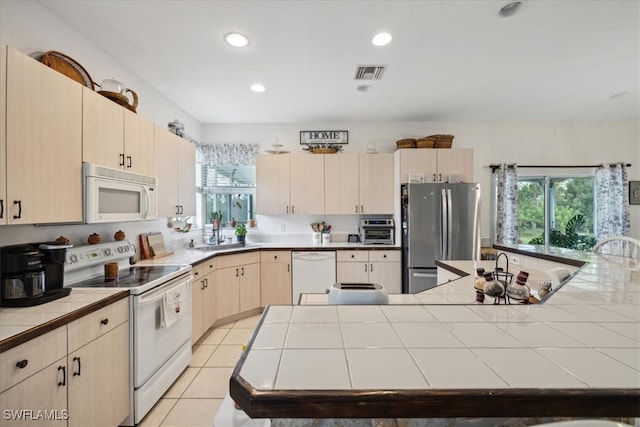 kitchen featuring tile counters, sink, light tile patterned floors, and white appliances